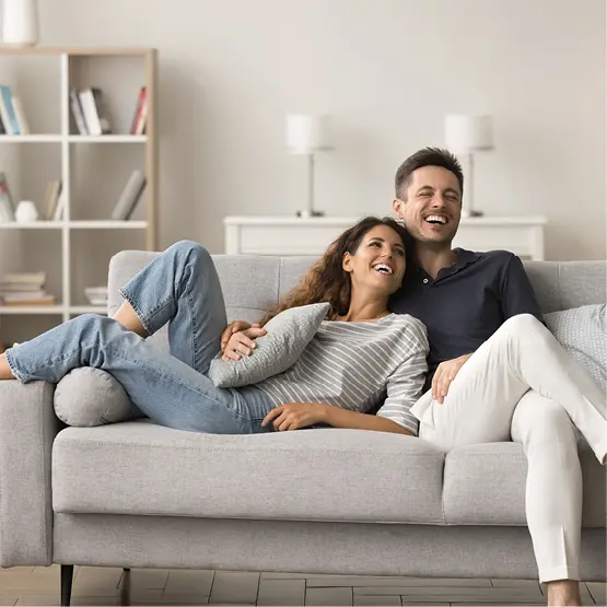 Zufriedenes Paar entspannt auf dem Sofa im Wohnzimmer nach erfolgreicher Küchenplanung und Montage. Komfort und Wohlfühlatmosphäre im eigenen Zuhause.